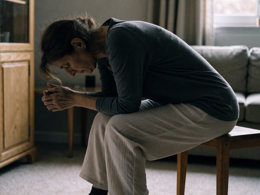 A woman sitting at home looking tired and low
